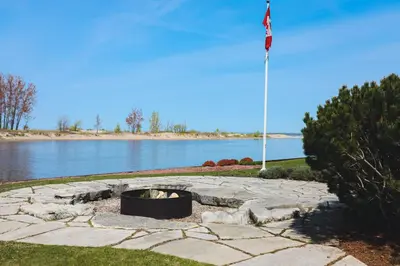 a flag pole and a fire pit next to a lake at The Lighthouse Cottage Four in Wasaga Beach