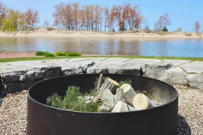 a large black barrel filled with logs next to a lake at The Lighthouse Cottage Four in Wasaga Beach