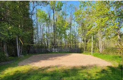 a dirt road with a volleyball net in a forest at Lovely waterfront private cottage with hot tub in Kawartha Lakes in Head Lake