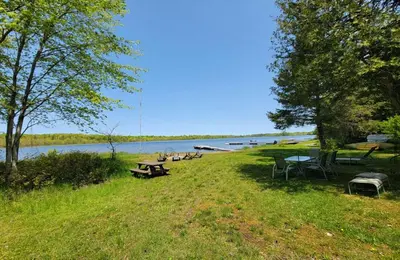 a park with picnic tables and benches next to a lake at Lovely waterfront private cottage with hot tub in Kawartha Lakes in Head Lake