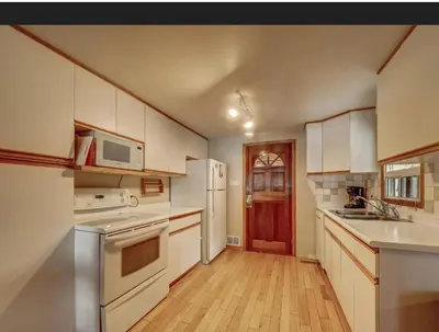 a kitchen with white appliances and a wooden floor at Lovely waterfront private cottage with hot tub in Kawartha Lakes in Head Lake