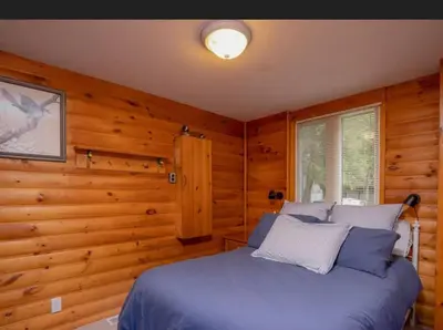 a bedroom with a blue bed in a wooden room at Lovely waterfront private cottage with hot tub in Kawartha Lakes in Head Lake