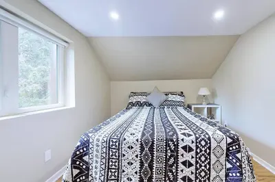 a bedroom with a bed with a black and white comforter at Hidden Farm Escape in the Heart of Kawarthas in Beaverton