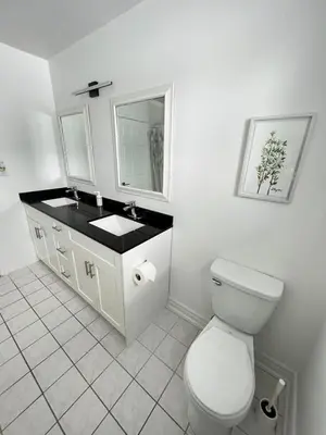 a white bathroom with a toilet and a sink at Letitia Heights !F Spacious and Stylish Private Bedroom with Shared Bathroom in Barrie