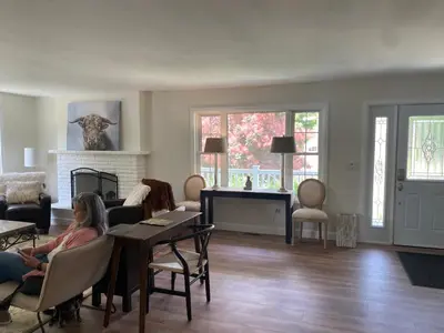 a woman sitting in a living room with a piano at Centre Gate House Licence# 117-2023 in Niagara on the Lake