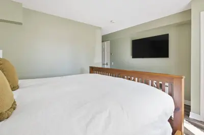 a bedroom with a white bed and a flat screen tv at 3BR Bright Mountain View Condo at Blue on Monterra in Blue Mountains