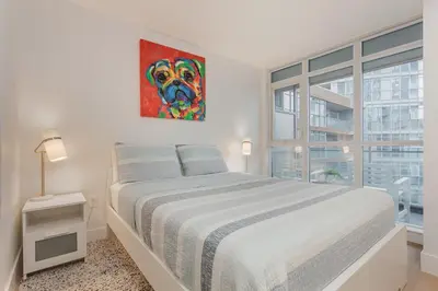 a white bedroom with a dog painting on the wall at Cozy 2BR Close to CN Tower & Harbourfront in Toronto