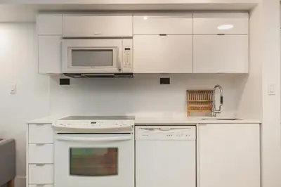 a kitchen with white cabinets and a microwave at Cozy 2BR Close to CN Tower & Harbourfront in Toronto