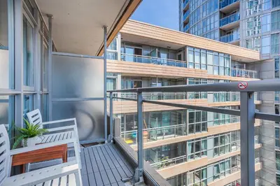 a balcony with two chairs and a building at Cozy 2BR Close to CN Tower & Harbourfront in Toronto