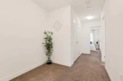 a hallway with white walls and a potted plant at Konia Suites in Orangeville