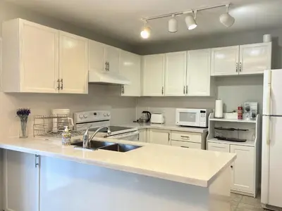 a kitchen with white cabinets and a sink and a refrigerator at Lake Simcoe 4 Bedroom Family Home Ideal Toronto Area Retreat in Innisfil