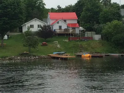 a house on the shore of a body of water at Balsam Lake Cottage 5 Bed room in Kawartha Lakes
