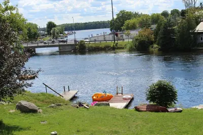 a river with a dock and a boat on it at Balsam Lake Cottage 5 Bed room in Kawartha Lakes