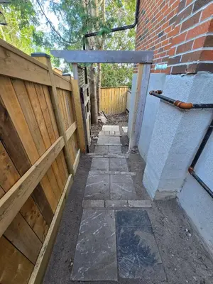 an alley with a wooden fence and a brick building at Private 2-Bedroom Minutes From Trent University in Peterborough