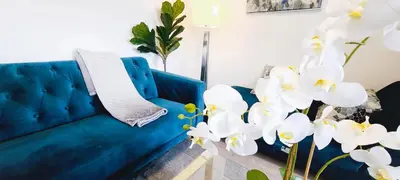 a blue couch in a living room with white flowers at Entire Luxury Suite 4Mins To Falls, Free Parking in Niagara Falls