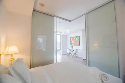 a bedroom with a white bed and a glass wall at Cozy 1 BR Air mattress CN Tower Ent District MTCC in Toronto