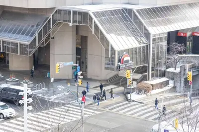 a group of people crossing a street in front of a building at LUX 2BR 1BA Steps to CN Tower W Parking included in Toronto