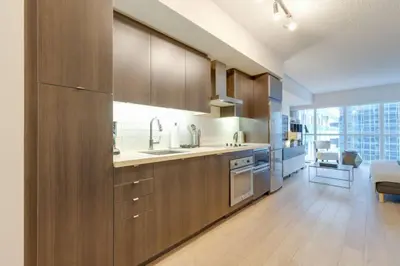 a kitchen with wooden cabinets and a large window at LUX 2BR 1BA Steps to CN Tower W Parking included in Toronto