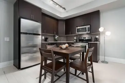a kitchen with a wooden table and a stainless steel refrigerator at Modern Condo 1 BD 1BA with a Sofabed Downtown in Toronto