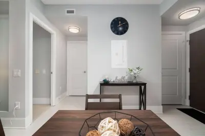 a living room with a table and a clock on the wall at Modern Condo 1 BD 1BA with a Sofabed Downtown in Toronto