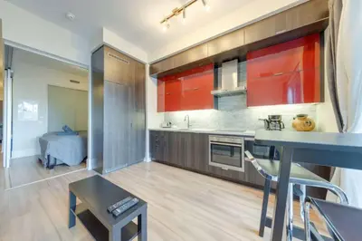 a kitchen with red cabinets and a blue table at 1 BR Furnished Condo with Balcony across CN Tower in Toronto