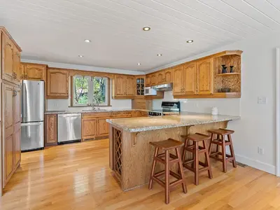 a kitchen with wooden cabinets and a large island with bar stools at Getaway Cottage LAKE FRONT Muskoka Room Kayaks in Dwight
