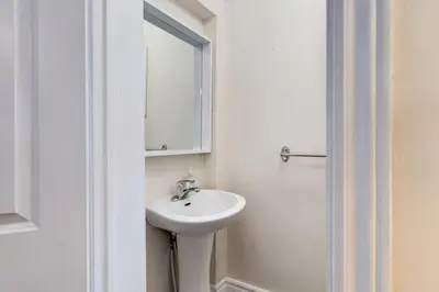 a white bathroom with a sink and a mirror at 3BR Casa close to Woodbine Beach with deck area and WFH in Toronto