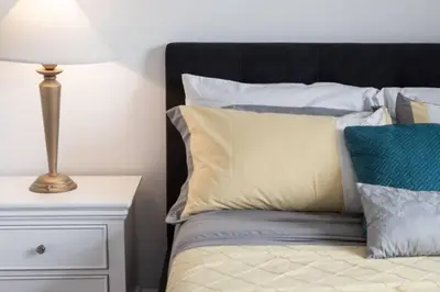 a bed with pillows and a lamp on a night stand at 3BR Casa close to Woodbine Beach with deck area and WFH in Toronto