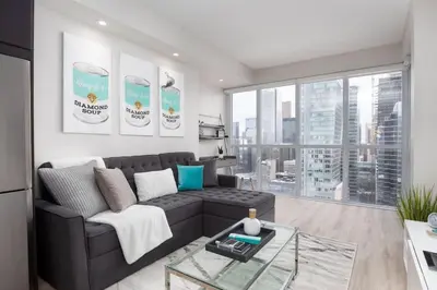 a living room with a couch and a large window at Luxury CN Tower View King Bed Balcony FREE PARK in Toronto