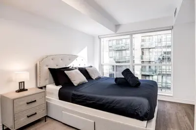 a bedroom with a bed and a large window at Urban APT with Highspeed WiFi Near shopping malls in Toronto