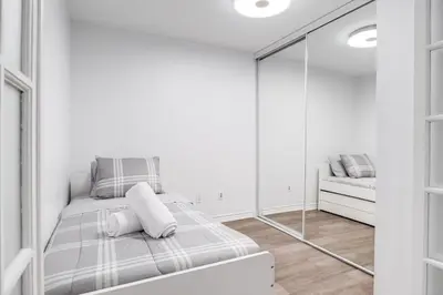 a white room with a bed and a mirror at Urban APT with Highspeed WiFi Near shopping malls in Toronto