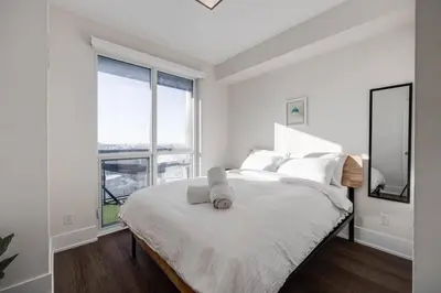 a white bedroom with a bed with a large window at Exec 2BR 2BTH w Million Dollar View of CN tower in Toronto
