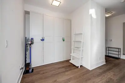 an empty room with white cabinets and wood floors at Exec 2BR 2BTH w Million Dollar View of CN tower in Toronto