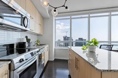 a kitchen with a large window with a view of the city at Skyline Waterfront 2BR plus 2BA wParking near MTCC in Toronto