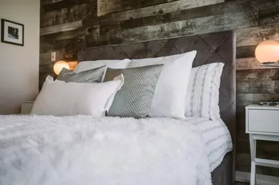 a bedroom with a white bed with a wooden wall at Skyline Waterfront 2BR plus 2BA wParking near MTCC in Toronto