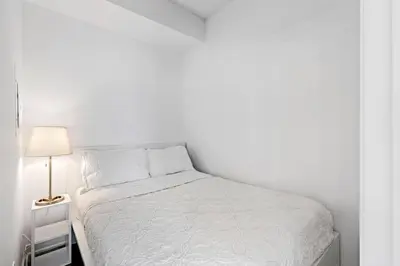 a white bedroom with a bed and a lamp at Comfy 2 BR 2 BA Ent District Work from home in Toronto