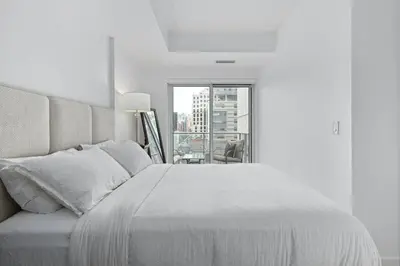 a white bedroom with a large bed and a window at Comfy 2 BR 2 BA Ent District Work from home in Toronto