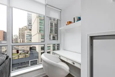 a living room with a white chair and a large window at Comfy 2 BR 2 BA Ent District Work from home in Toronto