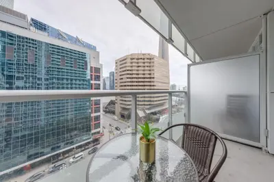 a glass table on a balcony with a view of a city at Stunning 1BR and Den Sleeps 6 Steps From CN Tower in Toronto