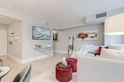 a living room with a white couch and a table at Stunning 1BR and Den Sleeps 6 Steps From CN Tower in Toronto