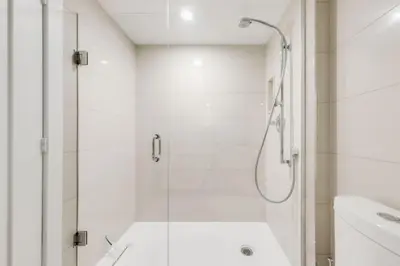 a white bathroom with a shower and a sink at Stunning 1BR and Den Sleeps 6 Steps From CN Tower in Toronto
