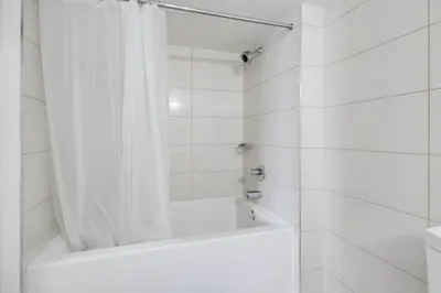 a white bathroom with a tub and a shower curtain at 2BR Fantastic View of CN Tower and Roger Centre in Toronto