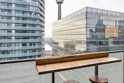 a bench on a balcony with a view of a building at Urban Lifestyle 1BR Suite w CN Tower and Lake view in Toronto