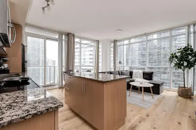 a kitchen and living room with a couch and a table at Cozy Downtown 2BR Suite near CN Tower with Balcony in Toronto