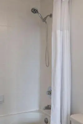 a shower in a bathroom with a white shower curtain at Cozy Downtown 2BR Suite near CN Tower with Balcony in Toronto