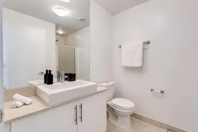 a white bathroom with a sink and a toilet at Cozy Downtown 2BR Suite near CN Tower with Balcony in Toronto