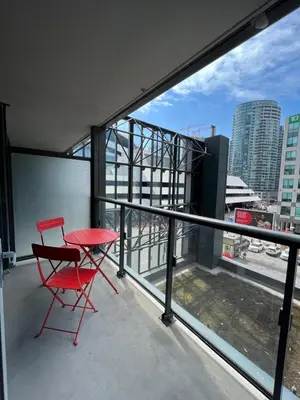 a red chair and a table on a balcony at Welcoming Downtown Condo with WFH setup Balcony in Toronto