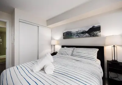 a bedroom with a bed with white sheets and pillows at Welcoming Downtown Condo with WFH setup Balcony in Toronto