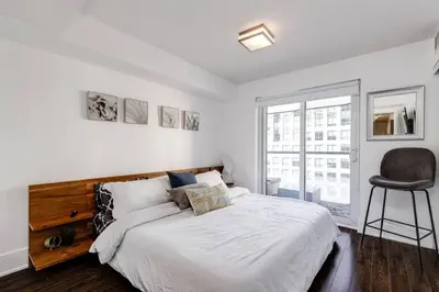a bedroom with a large bed and a chair at 3BR Rooftop Pool Gym Steps to MTCC and CN Tower with Parking in Toronto