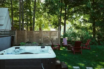 a hot tub in a yard with chairs and trees at Beach House 5 Star Gem with a Muskoka room and Yoga Studio in Innisfil